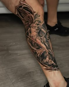 a man's leg with an angel and demon tattoo on the left side of his arm