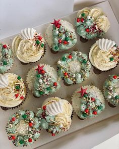 twelve cupcakes decorated with white frosting and christmas decorations on a baking sheet