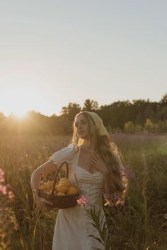 a woman standing in a field holding a basket of fruit