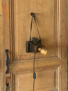 an old fashioned camera is hooked up to a wooden door with a light on it