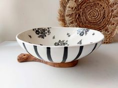 a black and white bowl sitting on top of a table next to a wooden spoon