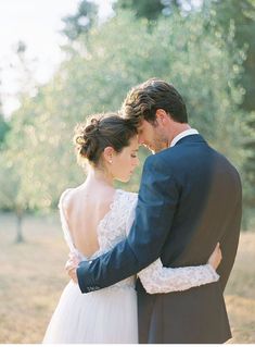 a bride and groom embracing each other in an open field