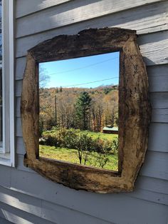 a mirror that is on the side of a house with trees in the back ground