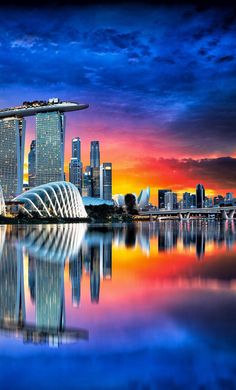 the singapore skyline is reflected in the water at sunset, with an orange and blue sky