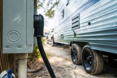 an rv parked on the side of a road next to a fence with a hose connected to it