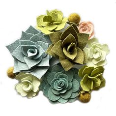 felt flowers arranged on top of each other in different colors and sizes, sitting on a sheet of paper