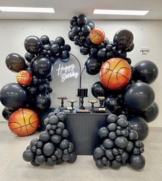 an arrangement of balloons and basketballs are displayed in the center of a room with a sign that says happy birthday