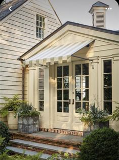 a white house with an awning over the door and steps leading up to it