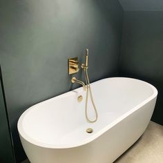 a white bath tub sitting inside of a bathroom next to a wall mounted faucet