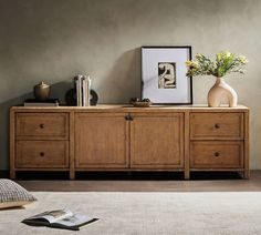 a wooden dresser with two vases on top of it next to a book shelf