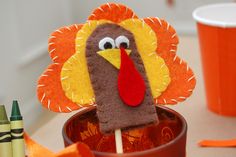 a paper turkey lollipop sitting on top of a cup