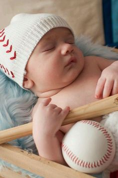 a baby is holding a baseball bat and wearing a knitted hat while laying in a crib