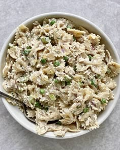 a bowl filled with pasta and peas on top of a white tablecloth next to a spoon