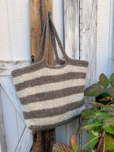 a brown and white striped bag hanging from a wooden door next to some green plants