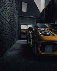 a yellow sports car parked in front of a brick building at night with its lights on