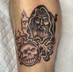 a man's leg with a black and grey tattoo on it, featuring a skull