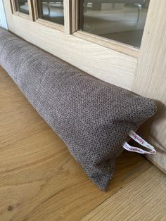 a brown pillow sitting on top of a wooden floor next to a door frame and window