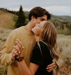 a man and woman hugging each other in the middle of a field