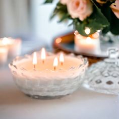 some candles are lit on a table with flowers