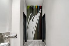 the hallway is painted with white and black lines on the wall, along with stainless steel urinals