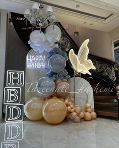 balloons are arranged on the floor in front of a staircase with a happy birthday sign