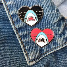 two shark heart shaped pins sitting on the back of a pair of jeans