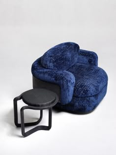 a blue reclining chair next to a black footstool on a white background