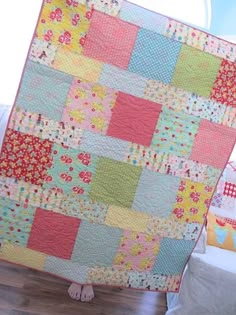 a woman standing next to a quilt on top of a bed