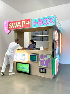 a man and woman standing in front of a box booth with the word swap on it