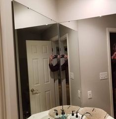 a man taking a selfie in front of a bathroom mirror with the reflection of himself