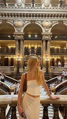 a woman in a white dress is standing on some stairs