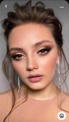 a woman with long hair and makeup looks at the camera while wearing large silver earrings