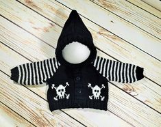 a black and white knitted sweater with skulls on it, sitting on a wooden floor