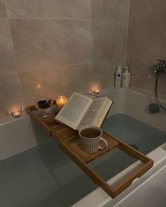 an open book on a tray in a bathtub with candles and tea light holders