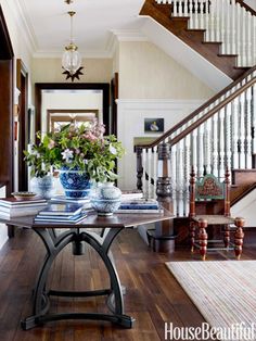 a table with two vases on top of it in front of a stair case