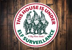 this house is under elf surveillance sticker on a wooden wall with wood planks