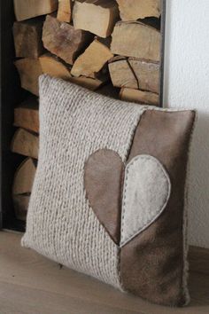 a heart pillow sitting on top of a wooden floor next to a pile of firewood