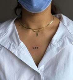 a woman wearing a face mask with the word art tattooed on her chest