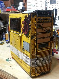 a yellow and black computer case sitting on top of a wooden table in a shop