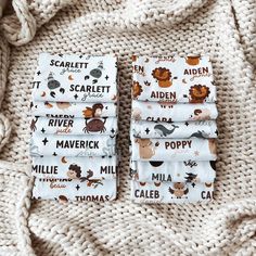 four folded napkins with animals on them sitting on a white knitted bed spread