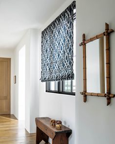 a wooden bench sitting under a window next to a mirror on the side of a wall