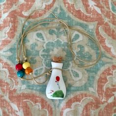 a bottle with some beads hanging from it's side on a tablecloth covered surface