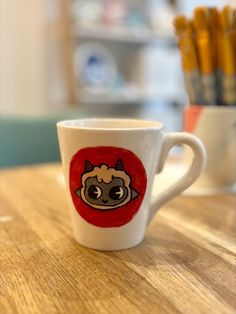 a coffee cup with an image of a pug on the front and side, sitting on a wooden table