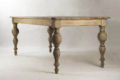 an old wooden table with turned legs on a plain white background is seen in this image