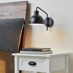 a black lamp on a white nightstand next to a bed