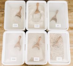 six plastic containers filled with sand and wooden spoons