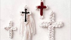 three crocheted crosses hanging on a wall with red and white tassels