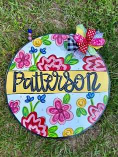 a painted plaque that says, patterson on it with flowers in the grass