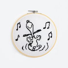 a cross stitch hoop with an image of a cat and music notes