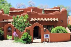 an adobe - style building with plants and trees around it